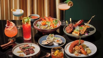 A variety of dishes and drinks on a table, including seafood, meats, and cocktails.