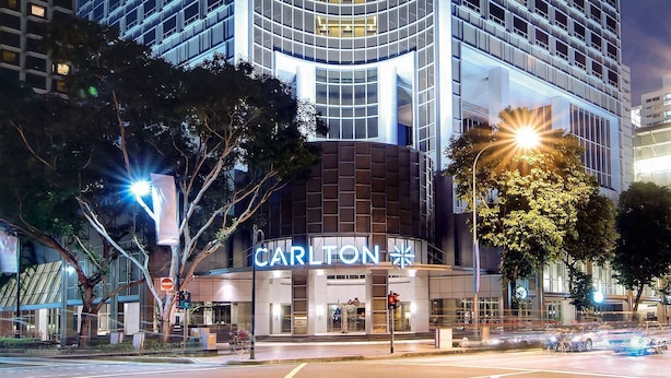 A tall hotel with a curved facade, illuminated signage, and a prominent 'Carlton' sign at the top. - Carlton Hotel Singapore (Singapore)