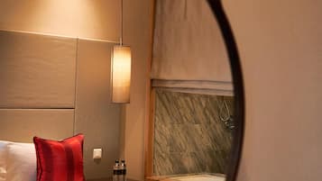 Una habitación de hotel con una cama, una mesita de noche, un espejo y una lámpara en la pared.