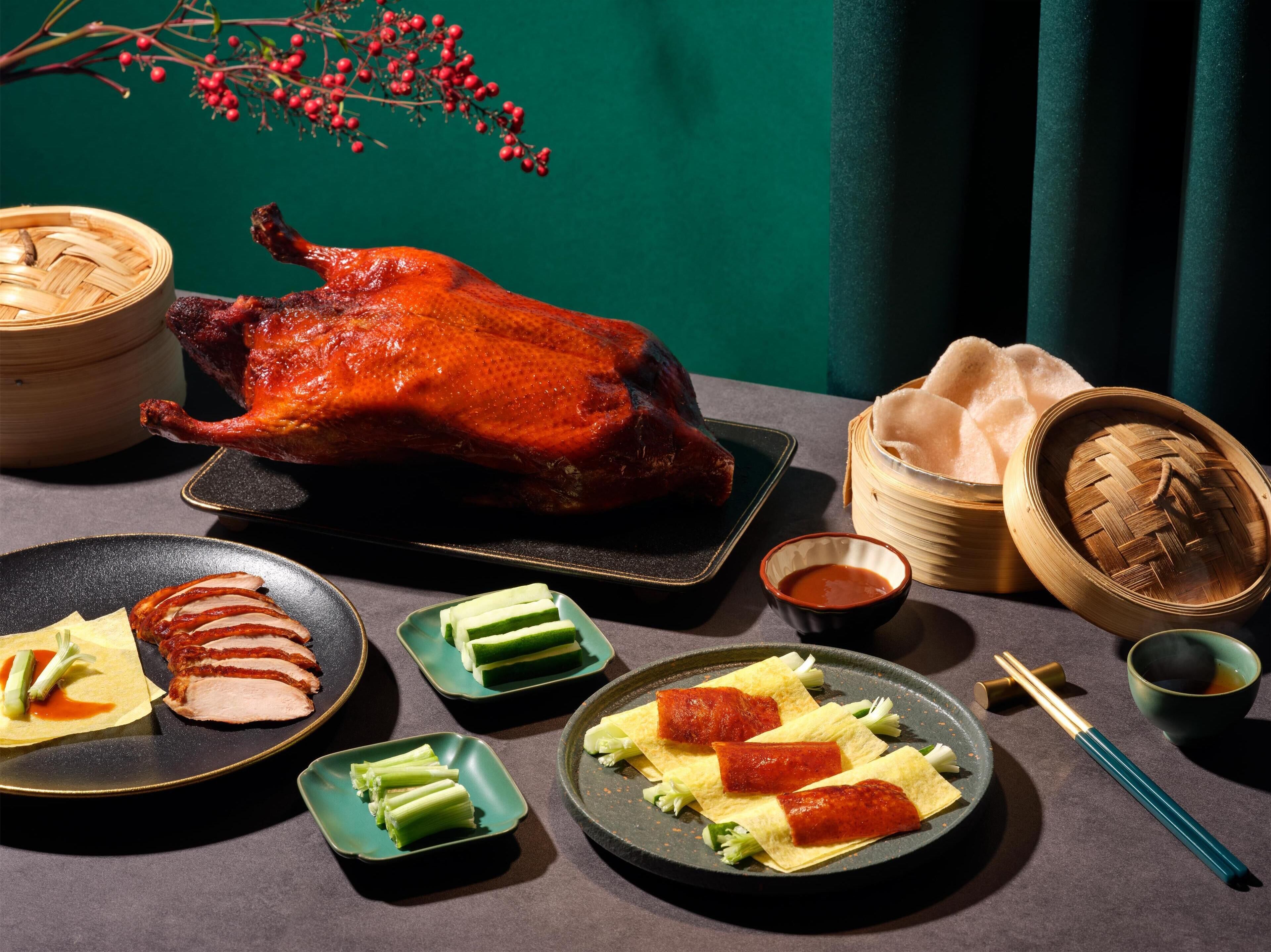 A table with a roasted duck, sliced meat, vegetables, and various dishes.