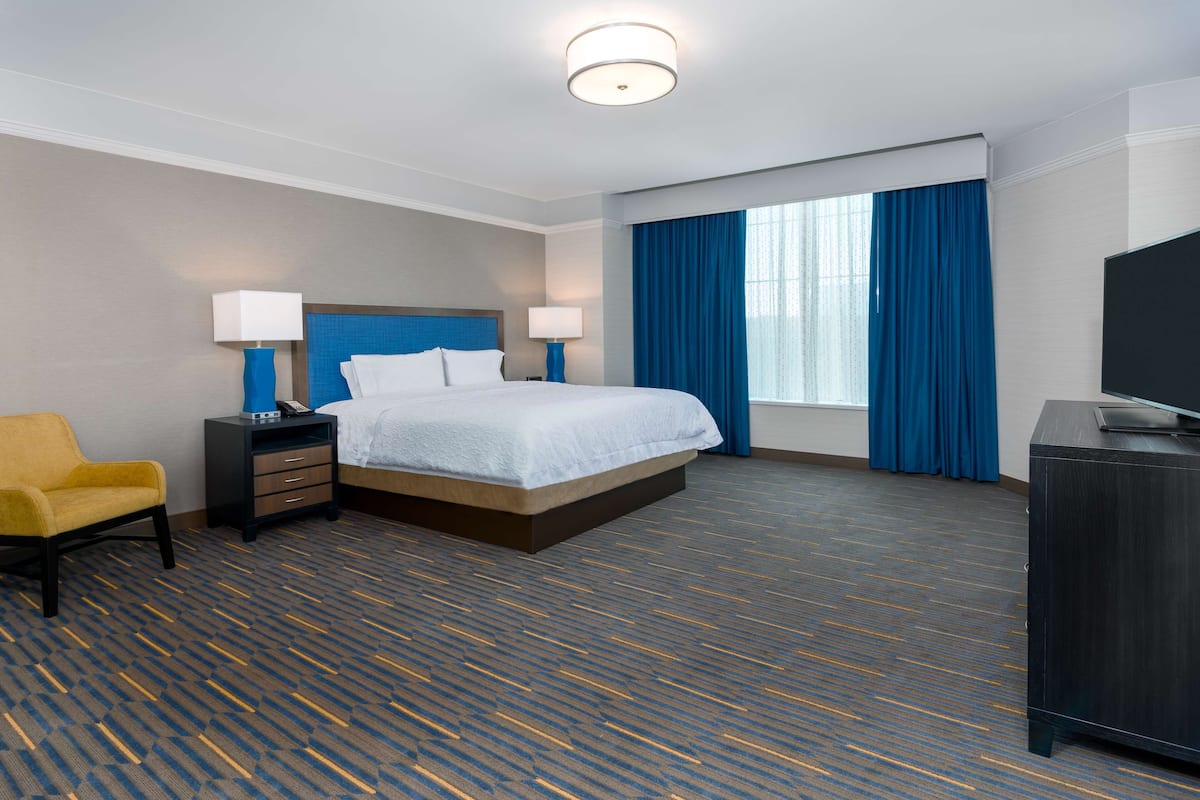 A hotel room with a bed, a desk, a chair, and a television.