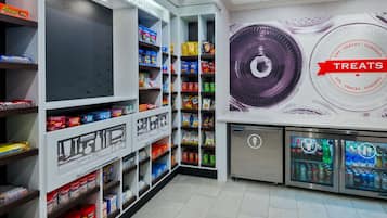 A snack and treat section with shelves stocked with various products, a refrigerated display case, and a wall mural advertising treats.