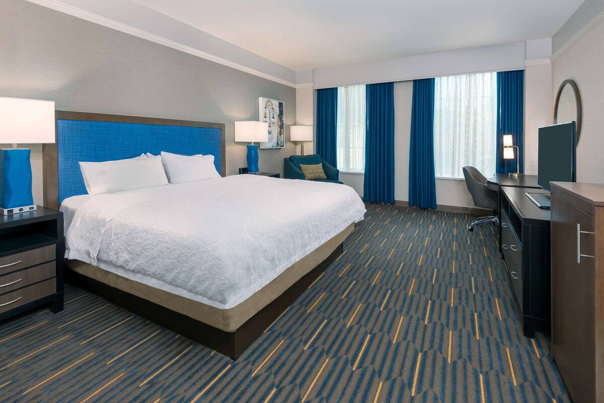 Une chambre d’hôtel avec un grand lit, un bureau, une chaise et un téléviseur.