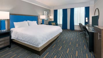 A hotel room with a large bed, a desk, a chair, and a TV.