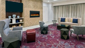 A modern living room with a fireplace, comfortable seating, and a herringbone-patterned wall. - Hampton Inn & Suites Buffalo Downtown (Buffalo)