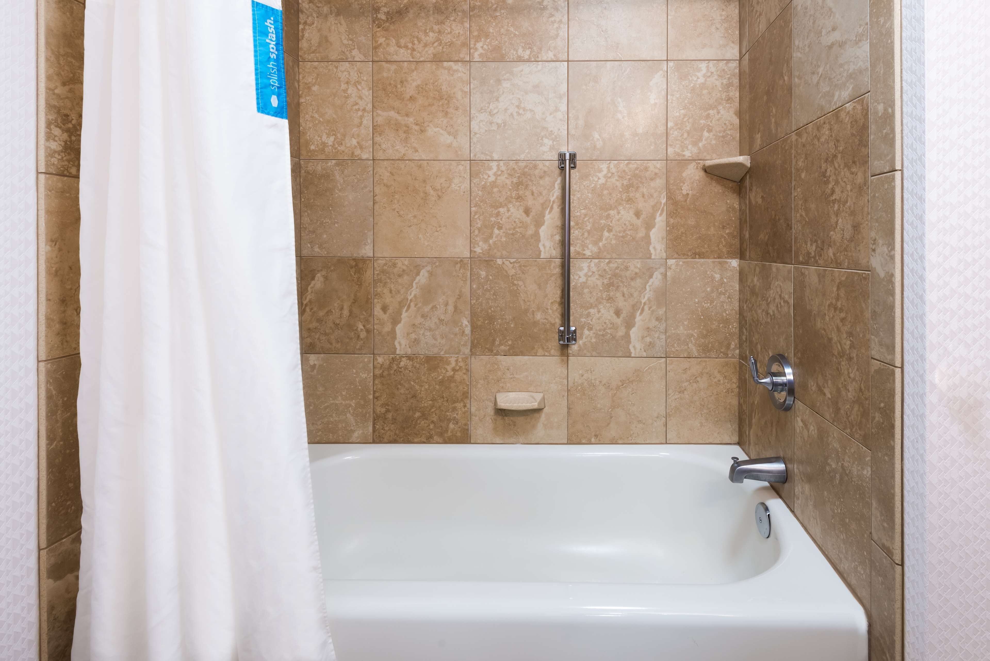 Un bagno con vasca, doccia e porta asciugamani.