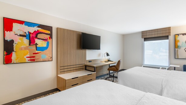 A hotel room with two beds, a desk, a TV, and artwork on the walls. - Hampton Inn Atlanta - Stockbridge (Stockbridge)