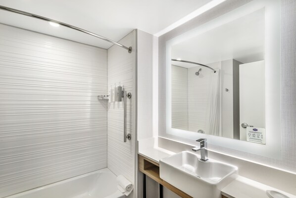 A modern bathroom with a walk-in shower, a large mirror, and a white sink.