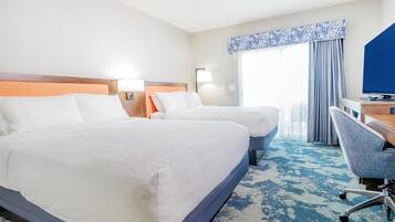 A hotel room with two beds, a desk, and a chair.