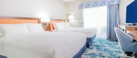 A hotel room with two beds, a desk, and a chair.