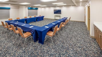 Un salón de conferencias con una larga mesa, sillas y piso alfombrado.