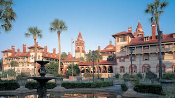 A historic building with arched windows and a fountain in the foreground.