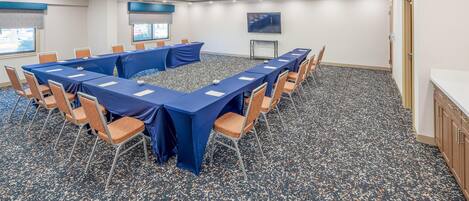 A conference room with a long table, chairs, and a carpeted floor.