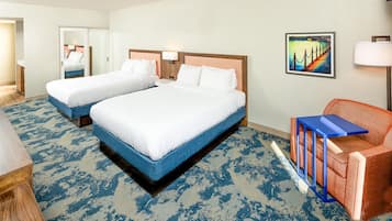 Une chambre d’hôtel avec deux lits, un bureau, une chaise et un tableau au mur.
