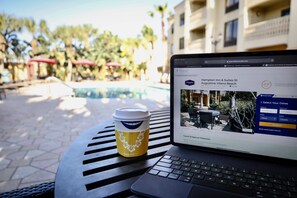 Una computadora portátil sobre una mesa, con una taza de café a su lado, mostrando un sitio web de un hotel.
