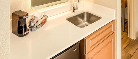 A compact kitchen with a sink, a coffee maker, and a refrigerator.