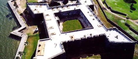 Vista aérea de una estructura fortificada con un patio central, rodeada por muros y un foso.