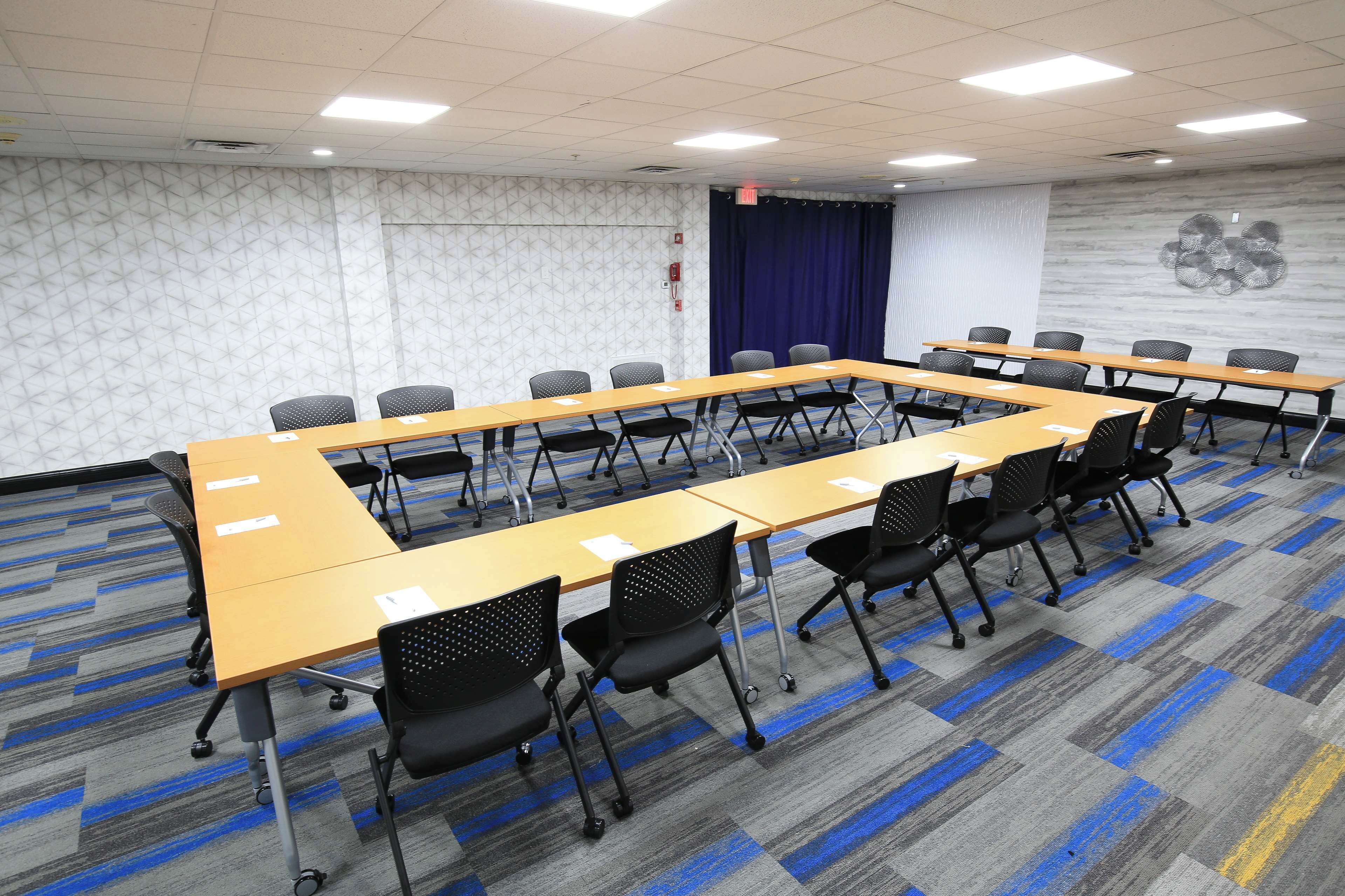 Una sala de conferencias con una mesa larga, varias sillas y una alfombra estampada.