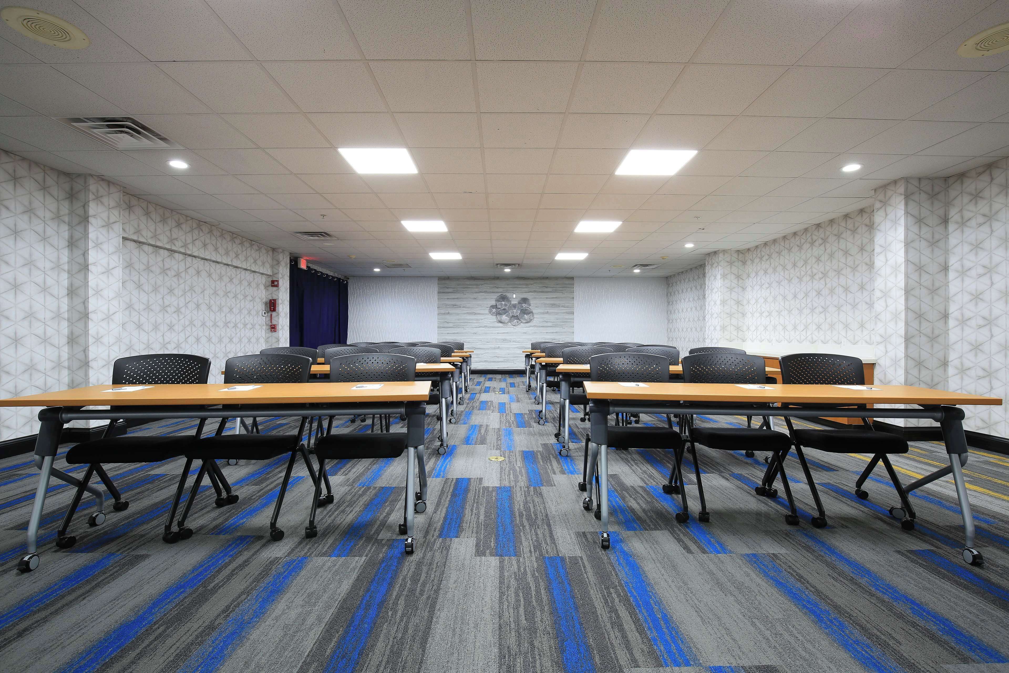Una sala de conferencias con una mesa larga, varias sillas y una alfombra estampada.
