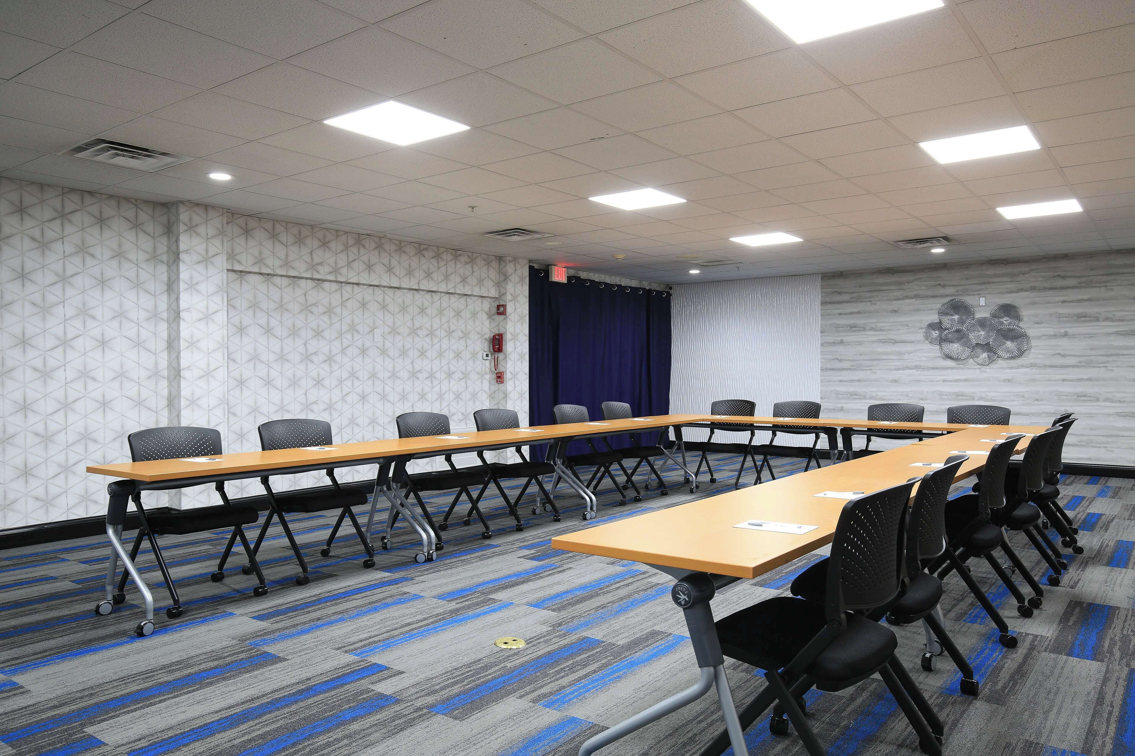 Une salle de conférence avec une longue table, de nombreuses chaises et un tapis à motifs.