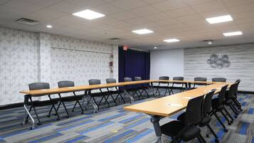 Une salle de conférence avec une longue table, de nombreuses chaises et un tapis à motifs.