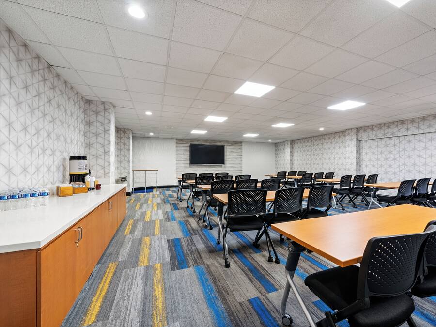 Un salón de conferencias con mesas, sillas, una pizarra y un mostrador con útiles.