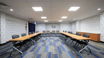 A conference room with a long table, chairs, and a patterned carpet.
