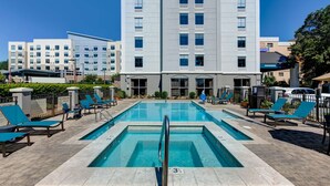 A swimming pool with lounge chairs and a building in the background. - Hampton Inn Biloxi (Biloxi)