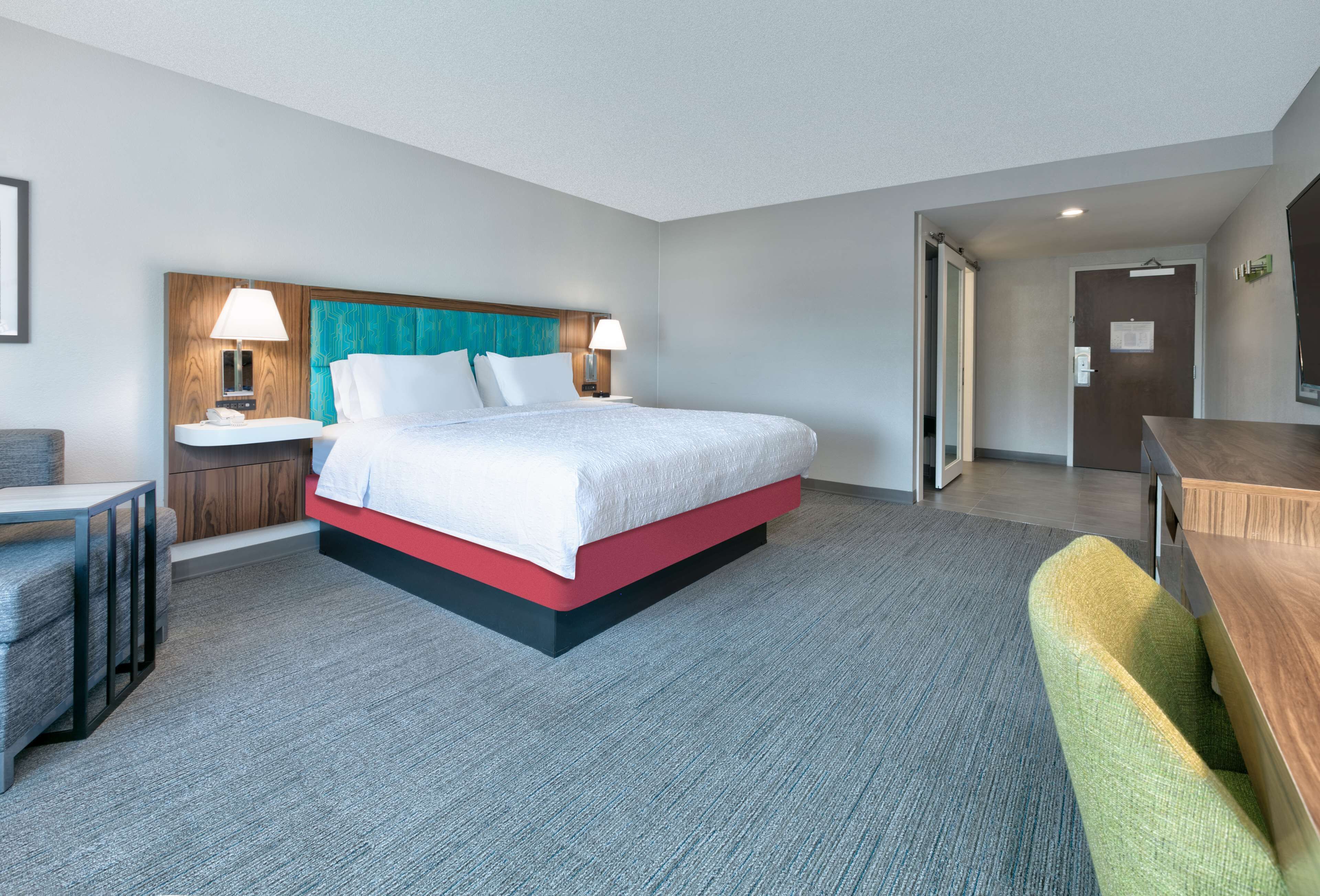 A hotel room with a bed, bedside tables, a desk, and a chair.
