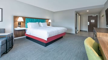 A hotel room with a bed, bedside tables, a desk, and a chair.
