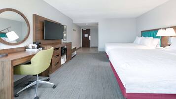 A hotel room with a bed, a desk with a chair, a television, and a mirror.