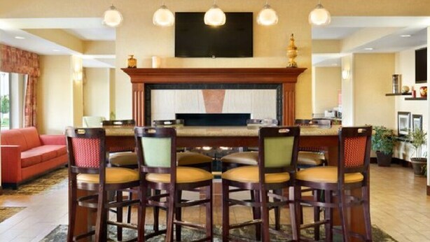A dining area with a long table and six chairs, a fireplace, and a television mounted on the wall.