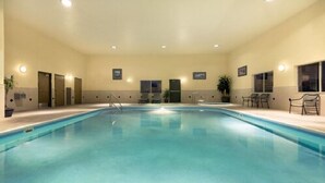 A swimming pool with a tiled floor, a changing room area, and a seating area with chairs.