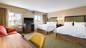 A hotel room with two beds, a TV, a desk, and a chair.