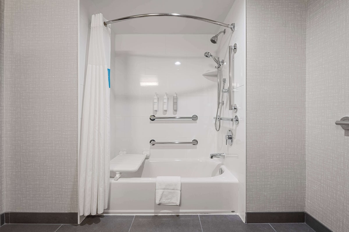 Ein modernes Badezimmer mit Badewanne, Dusche und Haltegriffen.