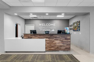 Una mesa de recepción con un cartel que dice 'Welcome to the Mother of States', un diseño de panel de madera y un quiosco digital.