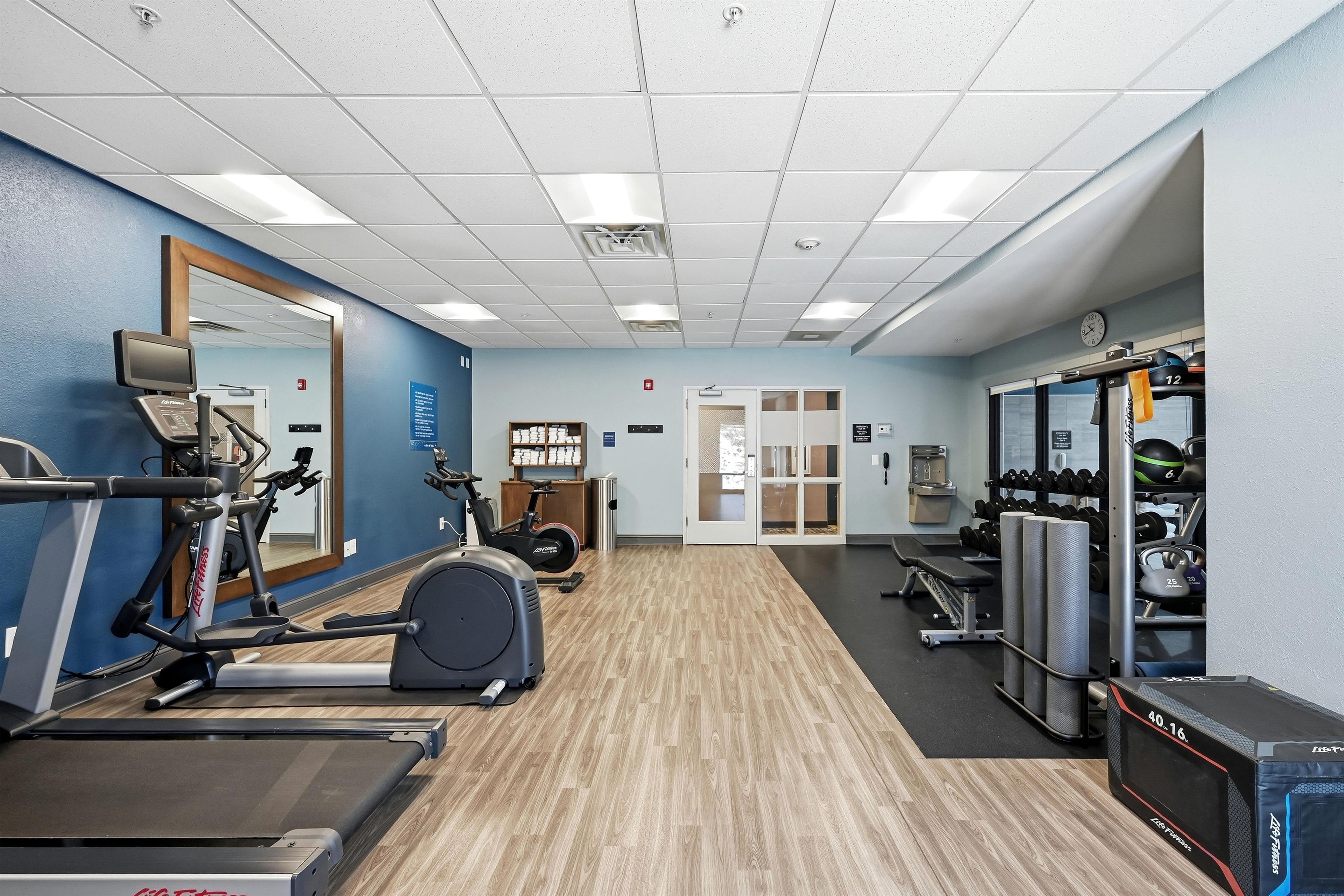 A gym with cardio equipment, weight machines, and a mirror.