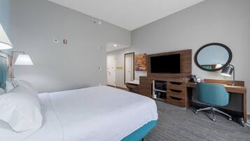 Une chambre d’hôtel avec un grand lit, un bureau avec une chaise, une télévision et un miroir.