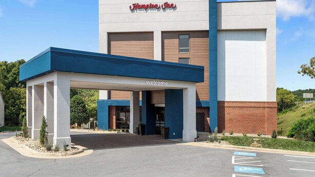 A Hampton Inn with a 'Welcome' sign, a covered entrance, and a parking lot with handicapped parking.