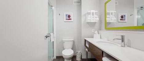 A modern bathroom with a glass shower enclosure, a toilet, a vanity with a mirror, and a towel rack.