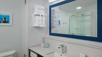 A modern bathroom with a large mirror, white sink, and towel racks.