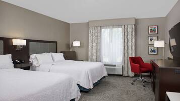 A hotel room with two beds, a desk, a chair, and a large window with curtains.