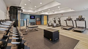 Uma academia com esteiras, elípticos e bancos de musculação.