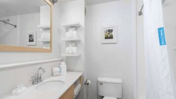 Une salle de bain moderne avec un lavabo blanc, un miroir, des toilettes et une douche.