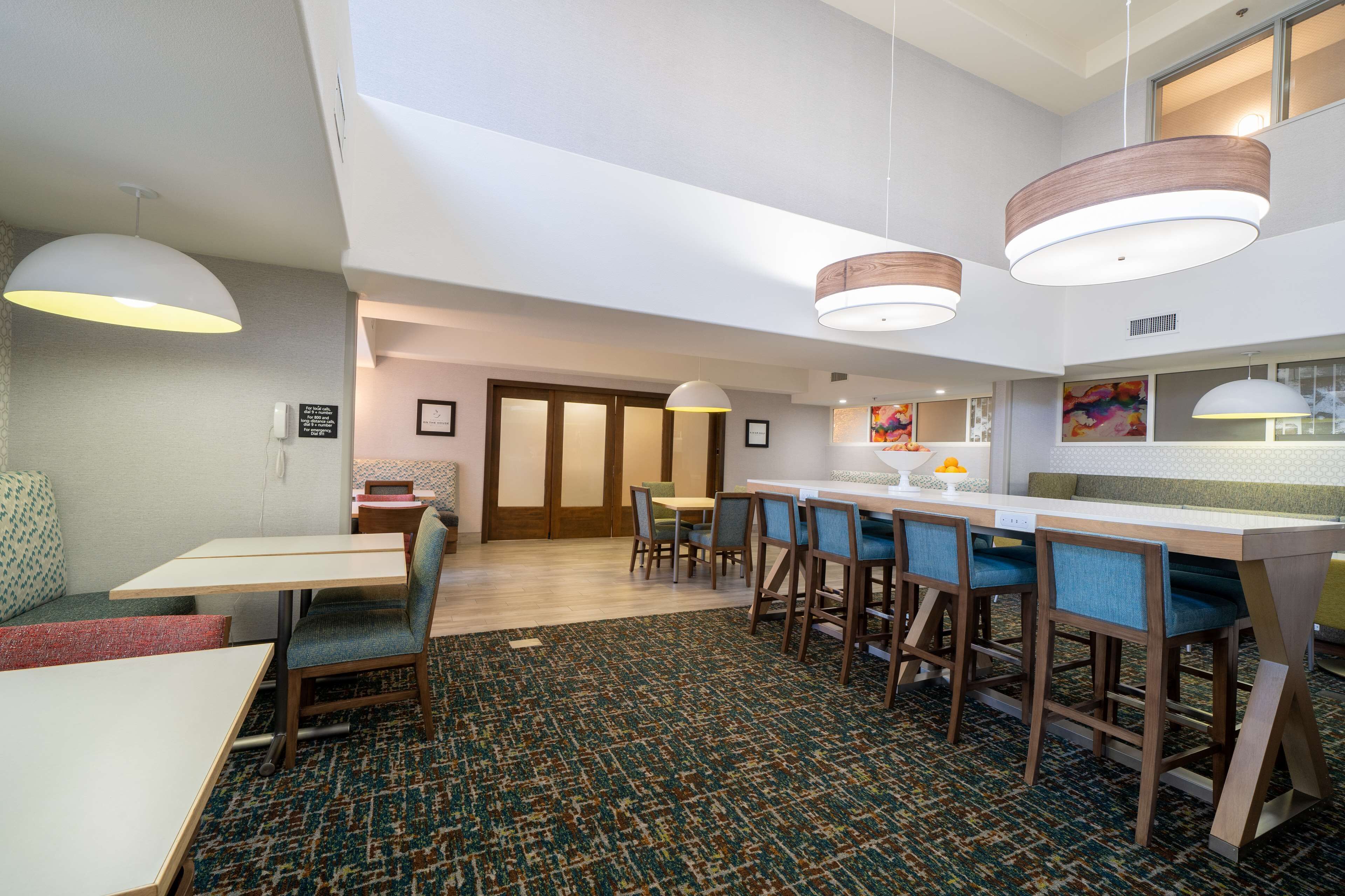 Un moderno vestíbulo de hotel con área de bar, zonas de estar y alfombra estampada.