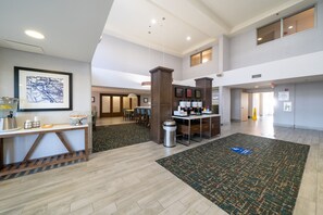 A spacious lobby with a coffee station, seating area, and a large rug.