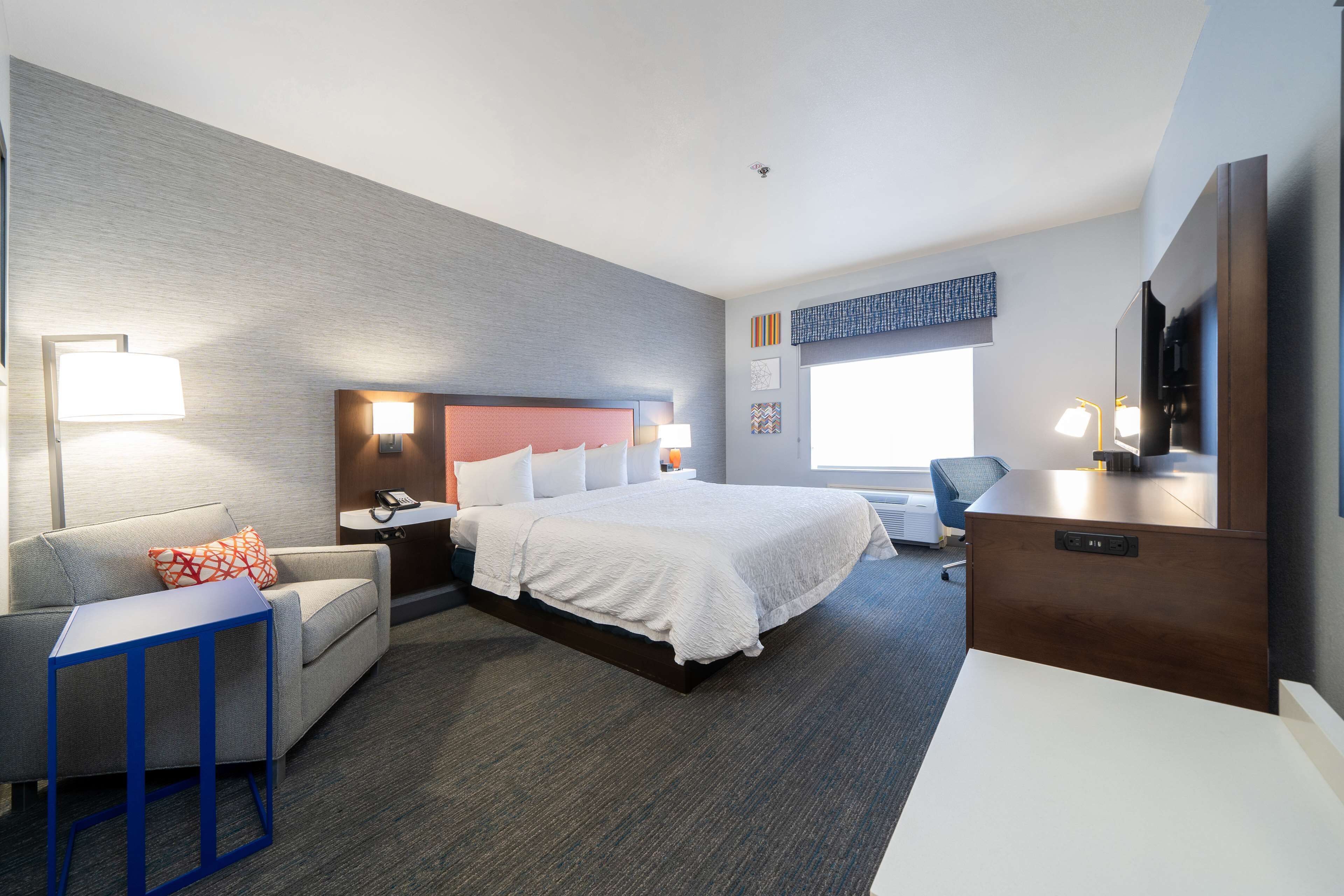 Ein Hotelzimmer mit einem großen Bett, einem Schreibtisch, einem Sessel, einer Couch und einem Fernseher.