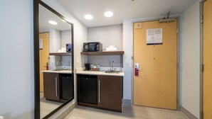 Uma kitchenette compacta com micro-ondas, pia e armários.