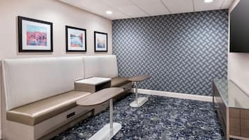 A modern waiting area with a sofa, small tables, and framed pictures on the wall.