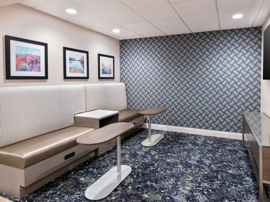 A modern waiting area with a sofa, small tables, and framed pictures on the wall.